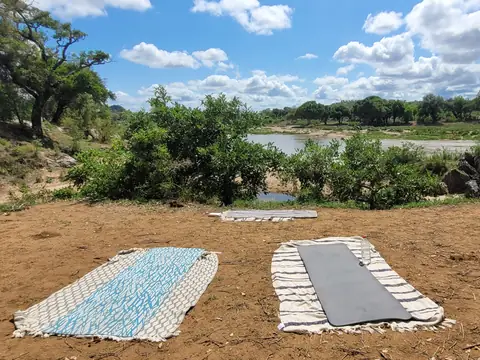 Two yoga mats facing a river, deep in the African bush