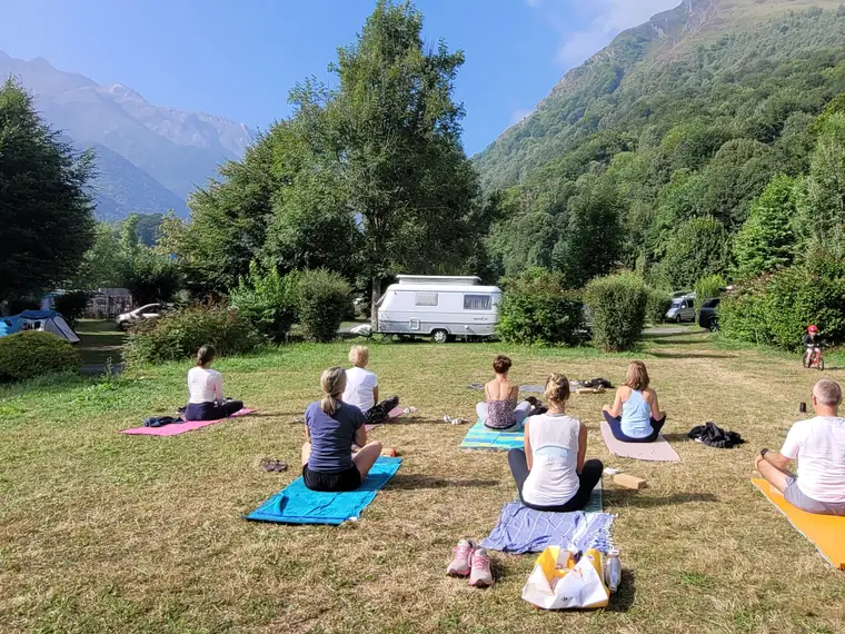 Un groupe assis en méditation sur l’herbe, face aux sommets