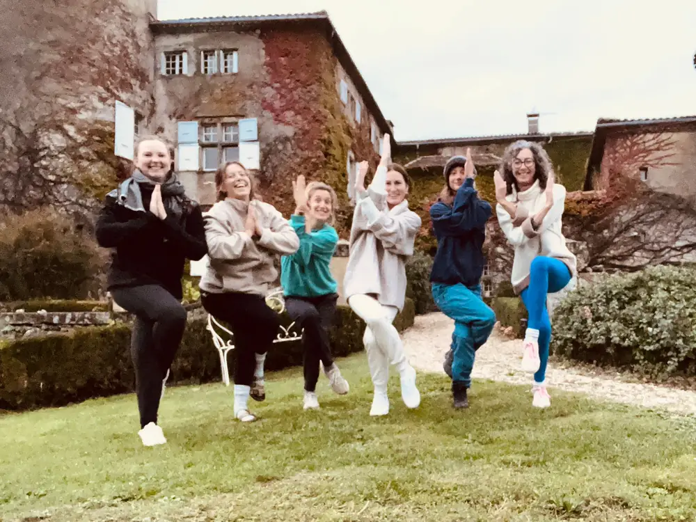 Un groupe joyeux en posture de l’arbre, mains jointes, dans le jardin d’une demeure ancienne