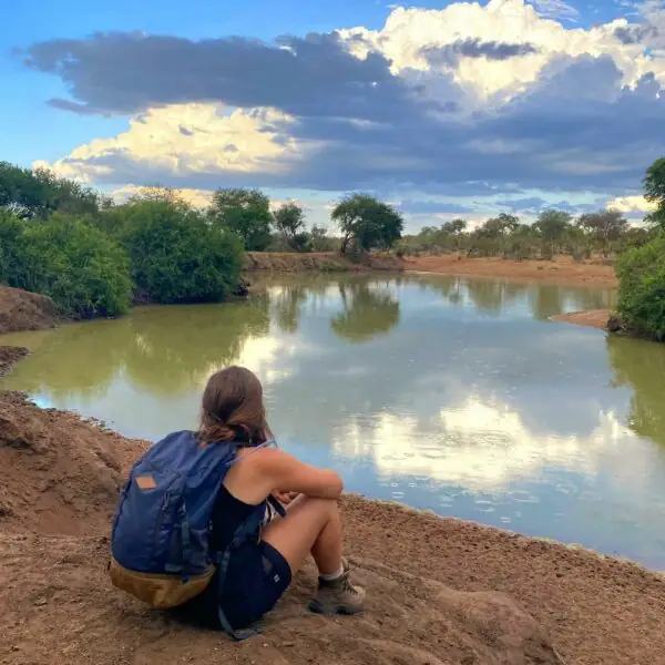 Une voyageuse assise au bord d’une rivière, au calme du soir