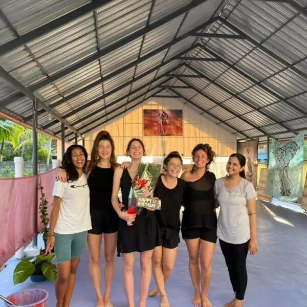 Un groupe de pratiquantes réunies dans une salle de yoga ouverte sur la végétation
