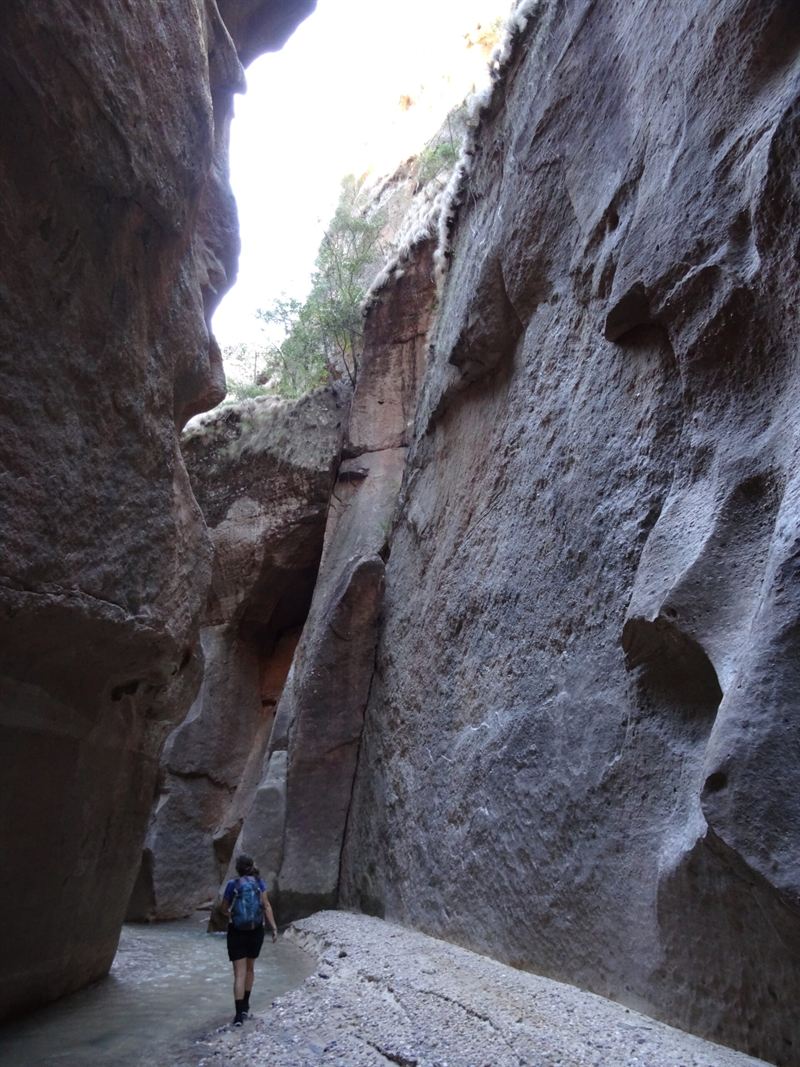 Une marcheuse au fond d’un étroit canyon de roche rouge