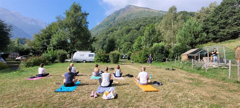 A group practising in a campsite meadow at the foot of the mountains