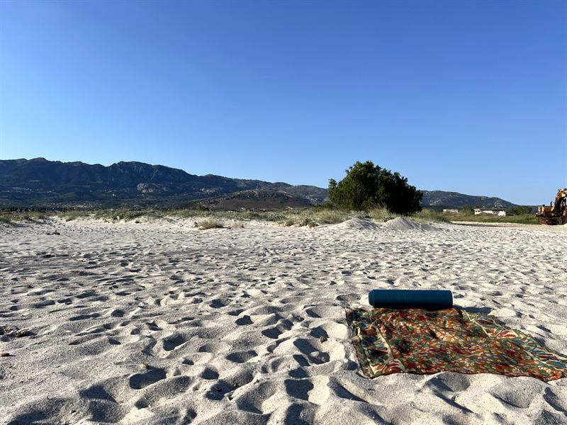A mat on a sandy beach, mountains on the horizon