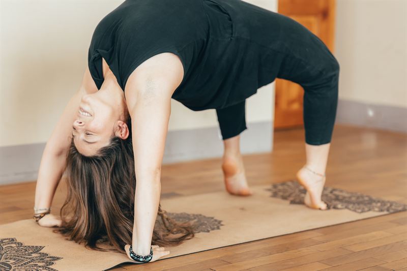 Une pratiquante en posture de la roue sur son tapis