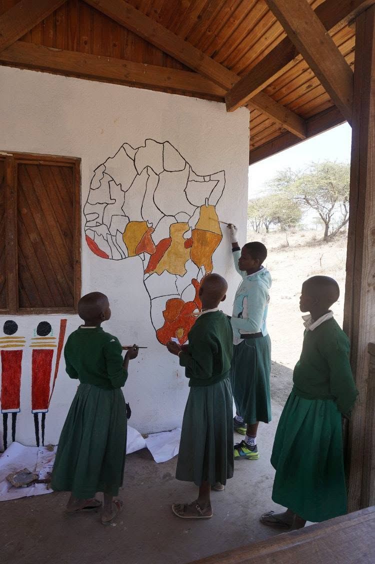 Schoolgirls in green uniforms in front of a map of Africa painted on their school wall
