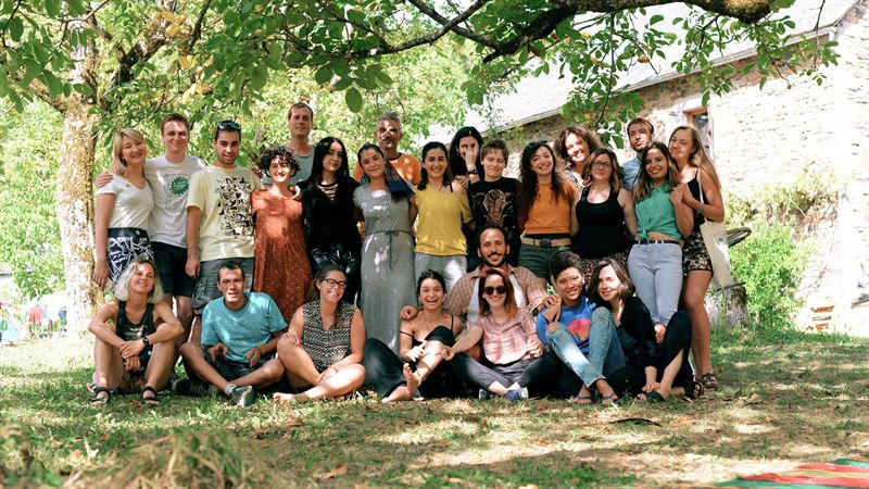 A large smiling group gathered under the trees