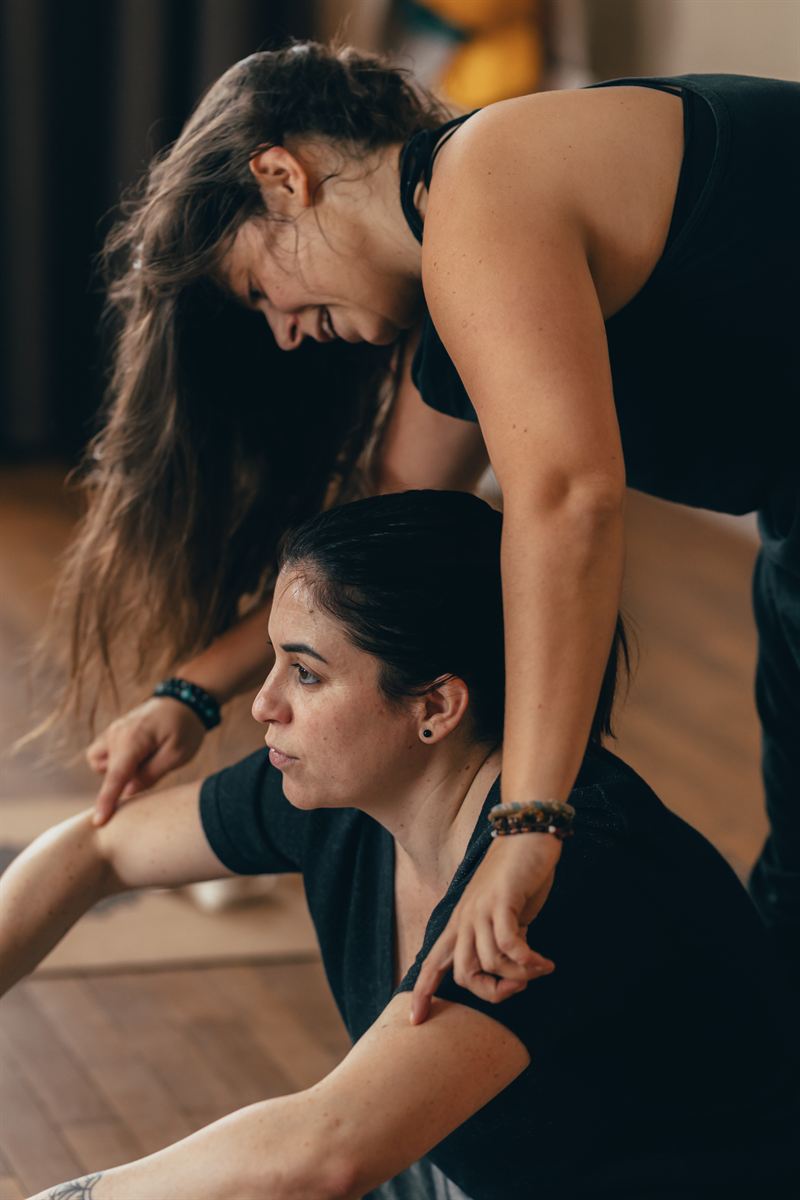 Pauline guide une élève dans une torsion assise