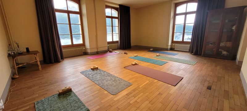 La salle de yoga, ses grandes fenêtres et son parquet ancien, avec les tapis déroulés