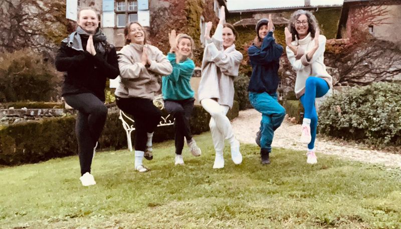 Le groupe de la retraite, souriant, en posture de l’arbre dans le jardin