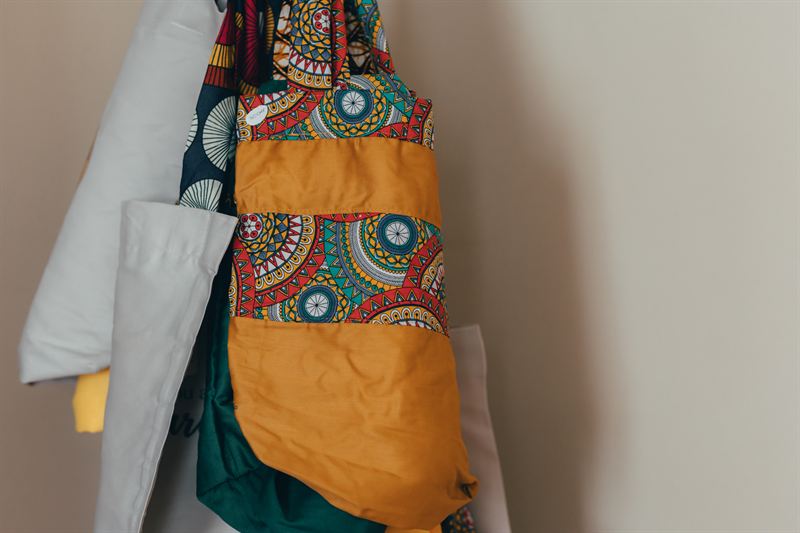 Des sacs en tissu wax aux motifs africains, suspendus à un mur
