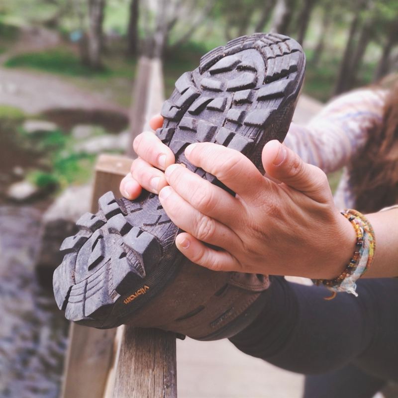 Les mains de Pauline sur la semelle de sa chaussure de randonnée