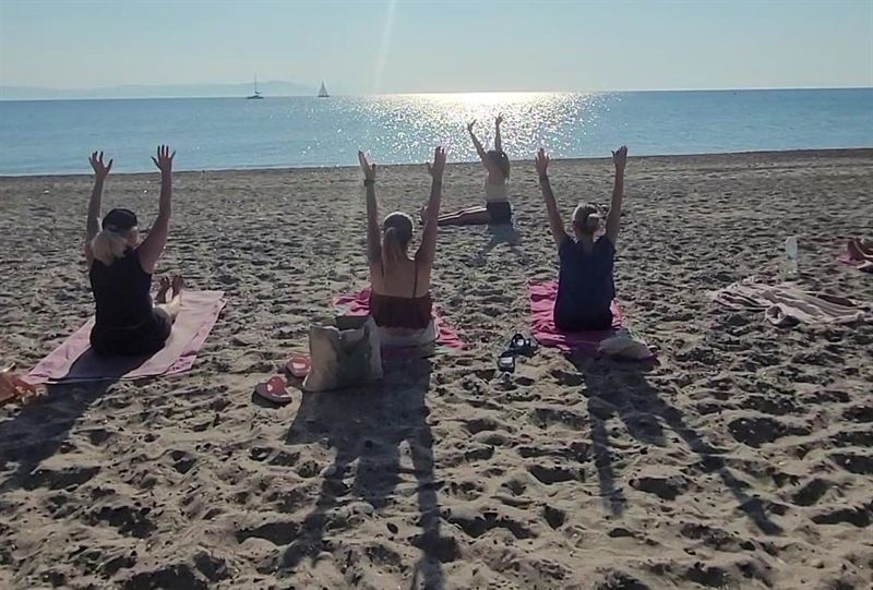 Un groupe bras levés vers le ciel sur une plage de sable, face à la mer, à Kos