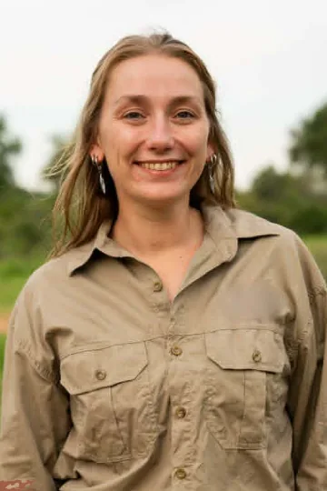 Kim, guide safari, souriante en tenue kaki dans la savane